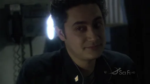 Felix Gaeta sonriendo en la penumbra en Battlestar Galactica
