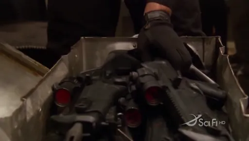 Una mano enguantada saca piezas de un cylon de una caja en Battlestar Galactica