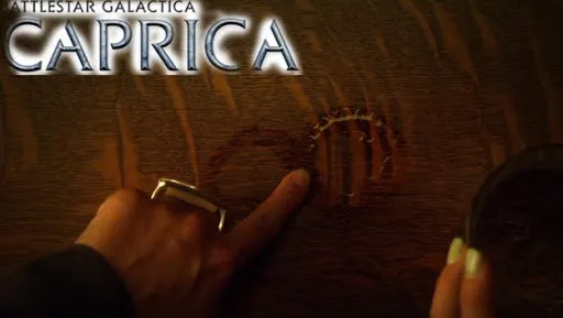 Una mano junto a un símbolo grabado en la madera con el logo de Caprica
