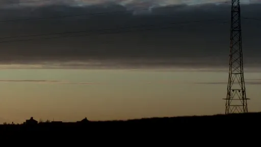 Una torre eléctrica recortada contra el cielo del atardecer en Hit & Miss