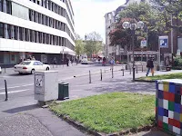 Una calle de Bonn con un coche blanco y un cubo de Rubik gigante